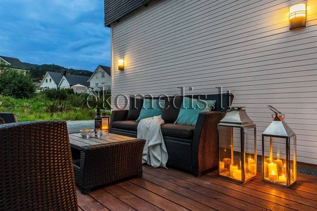 Sofagruppe og lykter på terrasse ved hvit liggende kledning, nabohus i bakgrunnen