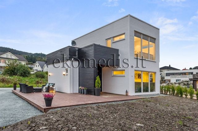 Moderne hus i to etasjer med hvit og svart kledning, store vinduer og terrasse