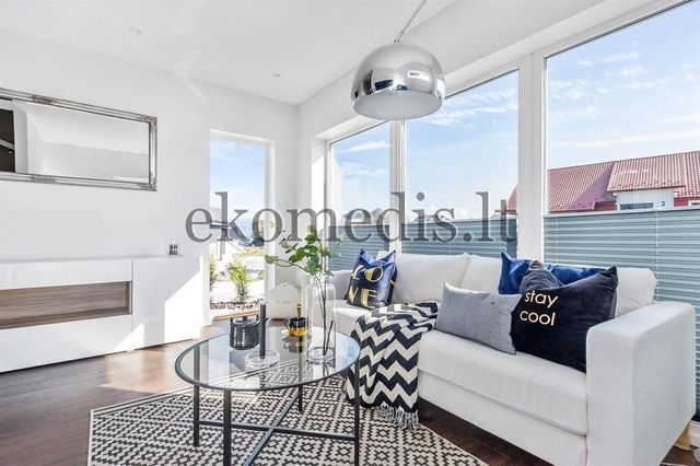 Lys stue med hvit sofa, rundt glassbord, buelampe og store vinduer