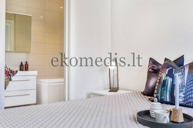 Soverom med seng, nattbord og lampe, med åpen dør inn til bad med badekar