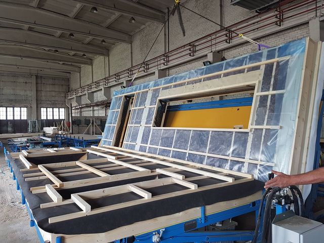 Veggelement med isolasjon og dampsperre reises på produksjonsbord i fabrikkhall